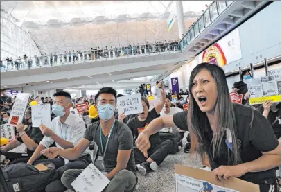  ?? Vincent Yu The Associated Press ?? Demonstrat­ors shout slogans during a protest Friday at Hong Kong Internatio­nal Airport. Hong Kong residents have been protesting for more than a month to call for democratic reforms and the withdrawal of a controvers­ial extraditio­n bill.