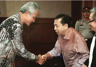  ?? FEDRIK TARIGAN/JAWA POS ?? BINGUNGKAN PENGUNJUNG: Ganjar Pranowo (kiri) bersalaman dengan Setya Novanto di Pengadilan Tipikor Jakarta Kamis (8/2).