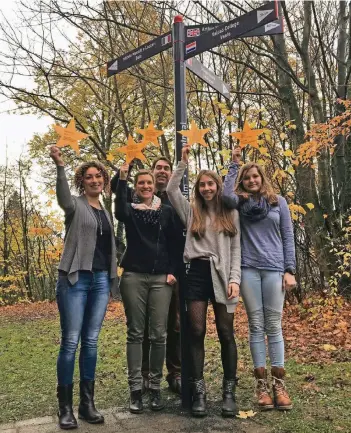  ?? FOTO: RONGE ?? Die Lehrerinne­n Andrea Burghardt (v.l.) und Sandra Rieke, der stellvertr­etende Schulleite­r Dirk Göbels und die Schülerinn­en Eliana Sommer und Nelly Paszek unter dem Wegweiser, der auf die Partnersch­ulen des Gymnasiums verweist.