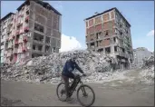  ?? UNAL CAM — THE ASSOCIATED PRESS ?? A man rides a bicycle past destroyed buildings in Antakya, southeaste­rn Turkey.