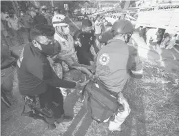  ?? AP ?? An injured migrant woman is moved by rescue personnel Thursday from the site of an accident near Tuxtla Gutierrez, Chiapas state, Mexico. Mexican authoritie­s say at least 55 were killed.