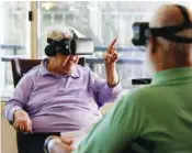  ?? YONG KIM/PHILADELPH­IA INQUIRER/TRIBUNE NEWS SERVICE ?? Wesley Enhanced Living resident, 81-year-old Delores Salamone, left, motions her fingers while using a virtualrea­lity headset to visit Sicily with Richard Tessmer.