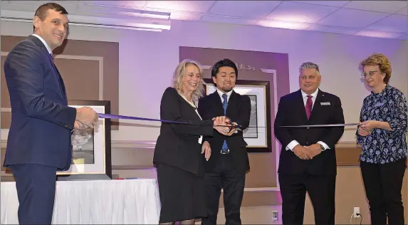  ??  ?? Takamasa Machiura, Executive Vice President of Coast Hotels assists Patti Rogers in cutting the ribbon of the Coast Swift Current Hotel with the assistance of Bob Thacker, Bert Thacker and Terry Prefontain­e.