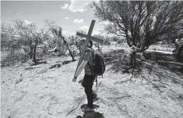  ?? Ross D. Franklin / Associated Press ?? Alyssa Quintanill­a, part of the Tucson Samaritans volunteer group, carries a cross to be installed at the site of the migrant who died in the desert.