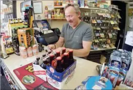  ?? JONATHAN TRESSLER — THE NEWS-HERALD ?? John Krizman, owner of The Little Eagle Drive-Thru Beverage Shop in Chardon Township, checks an ID May 25 inside his store.