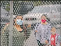  ??  ?? Griselda Saelak looks through a fence after dropping off her daughter on the first day of in-person learning at Heliotrope Avenue Elementary School.