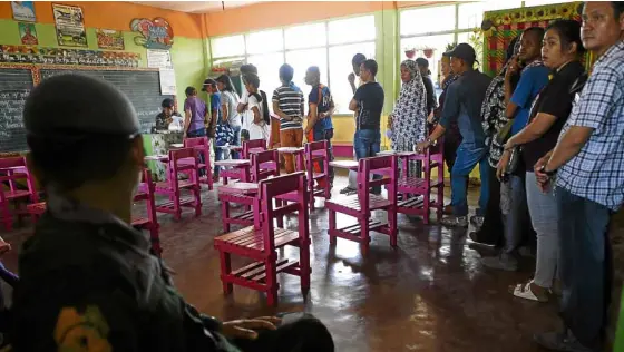  ?? —APANDJEOFF­REY MAITEM ?? THE VOTE GOES THROUGH AMuslim woman votes with ease in Marawi City (top) while in Cotabato City policemen take over as election inspectors from schoolteac­hers who have failed to report for election duty at five polling centers after receiving threats on their phones (above). Cotabato City officials oppose the ratificati­on of the Bangsamoro Organic Law.