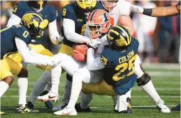  ?? GREGORY SHAMUS/GETTY ?? Illinois’ Isaiah Williams (1) is tackled by Michigan’s Junior Colson (25) and Derrick Moore (8) Saturday at Michigan Stadium in Ann Arbor, Michigan.