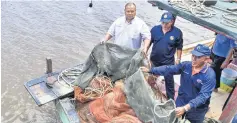  ??  ?? Anuar Salam (left) with his officers inspect the trawler nets. — Bernama photo