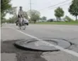  ??  ?? A cyclist veers out into traffic to avoid a raised edge that surrounds a utility cover on the north side of Rathburn Rd., east of Kipling Ave.