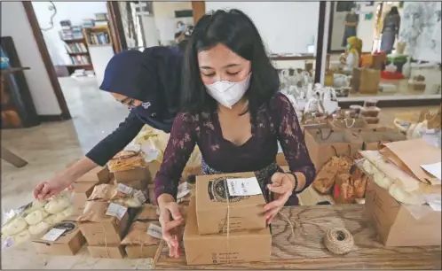  ?? (AP/Achmad Ibrahim) ?? Reny Ajeng (center), one of the organizers of Pahingan Sunday Market, packs food made by tenants to shipped to customers in Jakarta, Indonesia.