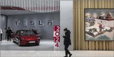  ?? (Bloomberg News WPNS) ?? A shopper passes a Tesla Inc. showroom in a Beijing shopping mall.