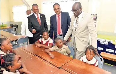  ?? CONTRIBUTE­D ?? Minister of Education, Youth and Informatio­n, Ruel Reid (right), interacts with students at Mineral Heights Primary School in Clarendon after a ceremony last week to officially hand over 12 new classrooms. Looking on (from left) are principal of the school, Lanzeford Howell; and managing director, Jamaica Social Investment Fund (JSIF), Omar Sweeney. The new classrooms have facilitate­d the transition of the school from the shift system.