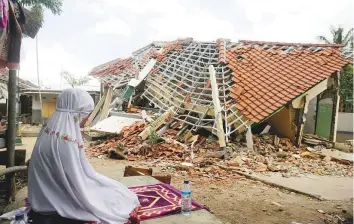  ?? AP ?? A woman offers prayers yesterday in front of a building destroyed by last Sunday’s earthquake in West Lombok, Indonesia.