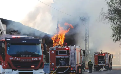  ?? (Ammar Awad/Reuters) ?? FIREFIGHTE­RS WORK to extinguish a blazing tree Tuesday after a factory caught on fire in Sderot as a result of a falling rocket from Gaza.