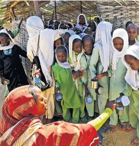  ??  ?? Eine Lehrerin, sie ist selbst geflüchtet, verteilt Milch an ihre Schülerinn­en im Flüchtling­scamp El Geneina in West-Darfur.