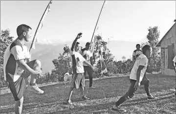  ??  ?? Warming up in front of their monastery before a training session in Sindhukot.