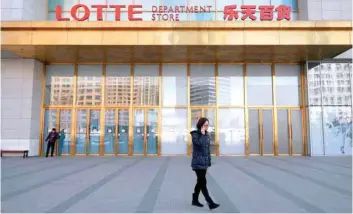  ?? — Reuters ?? A woman speaks on the phone while walking past Lotte department store in Beijing, China.