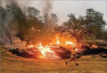  ?? NOAH BERGER / AP ?? A firefighte­r runs past flames while battling the Glass Fire in a Calistoga, Calif., vineyard on Thursday.