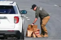  ?? Julio Cortez / Associated Press ?? A sheriff ’s deputy from Frederick County, Md., handles paper bags containing evidence linked to Tuesday’s shootings.