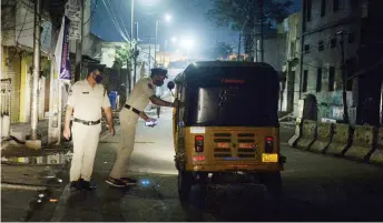  ?? — AFP photos ?? Police personnel checks an auto rikshaw along a deserted road during a night curfew imposed by the state government amidst rising Covid-19 coronaviru­s cases in Hyderabad.