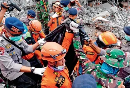  ?? AFP ?? Members of a search and rescue team carry the body of a quake victim found amongst the rubble in Bangsal, northern Lombok island on Wednesday, three days after the area was struck by an earthquake. —