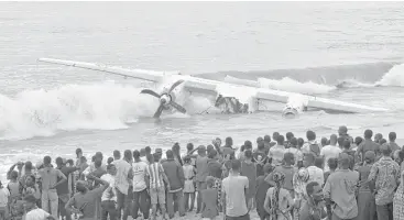  ?? Sia Kambou / AFP / Getty Images ?? People gather Saturday at the beach of Port-Bouet in Abidjan, Ivory Coast, to view the wreckage of a cargo plane that crashed with 10 crew members from France and Moldova onboard.