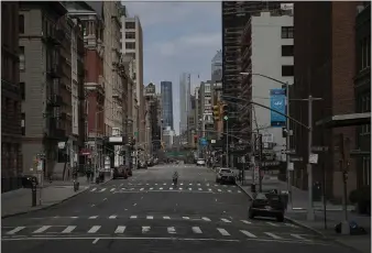  ?? WONG MAYE-E — THE ASSOCIATED PRESS ?? A cyclist rides his bicycle down the middle of a main road in New York City on Sunday. The mayor prepared Sunday to order nonessenti­al workers behind closed doors in an attempt to slow the coronaviru­s.