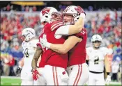  ?? RON JENKINS / GETTY IMAGES ?? Tight end Troy Fumagalli (right) is hugged by teammates after his 8-yard TD reception as Wisconsin takes a 24-10 lead early in the fourth quarter.