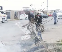  ??  ?? EMERGENCY MEASURE. Sebokeng resident Isaac Bobo Nkosi puts out a fire with a bucket of water at Zone 10 yesterday.