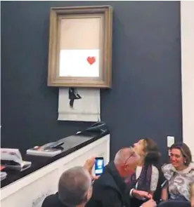  ?? PIERRE KOUKJIAN ASSOCIATED PRESS ?? Sitôt La petite fille au ballon rouge adjugée, l’oeuvre de Banksy a glissé hors de son gros cadre pour être à moitié réduite en bandelette­s par une déchiquete­use dissimulée.