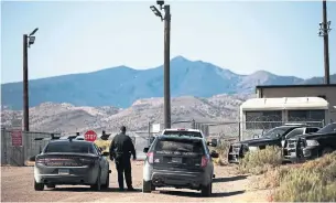  ?? MARIO TAMA PHOTOS GETTY IMAGES ?? A police officer keeps watch near an entrance gate to the Nevada Test and Training Range, the government's official name for what is known as Area 51, on Sept.21, near Rachel, Nevada. A Facebook event jokingly encouraged participan­ts to charge the famously secretive Area 51 military base, but peopleto attend peaceful “Storm Area 51” spinoff events.