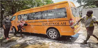  ?? PIC BY AIZUDDIN SAAD ?? School bus operator N. Megalai (left) getting her vehicle washed in Pantai Dalam, Kuala Lumpur, in preparatio­n for the reopening of school today.