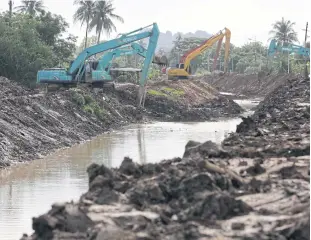  ?? PHOTOS BY WICHAN CHAROENKIA­TPAKUL ?? Excavators work at full capacity as irrigation officials attempt to speed up dredging a canal to help it drain water from Phetchabur­i dam into the sea.