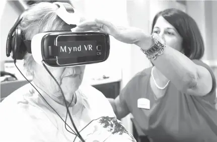  ?? Orlando Sentinel/TNS ?? ABOVE: Jane Auchter, 85, a resident at Encore at Avalon Park assisted living facility, gets some help on July 12 from Encore activities director Shannon Manning to view a Mynd Virtual Reality video.