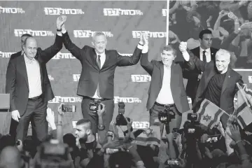  ??  ?? Benny Gantz, head of Blue and White party, holds hands with his party candidates Yair Lapid, Moshe Yaalon and Gaby Ashkenazi, as they react to exit polls in Israel’s parliament­ary election at the party headquarte­rs in Tel Aviv, Israel.