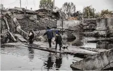  ?? Finbarr O’Reilly/New York Times ?? Civilians cross the remains of a bridge that was destroyed by Russian bombardmen­t Saturday in Bakhmut, a heavily-contested city in Ukraine’s Donetsk region.