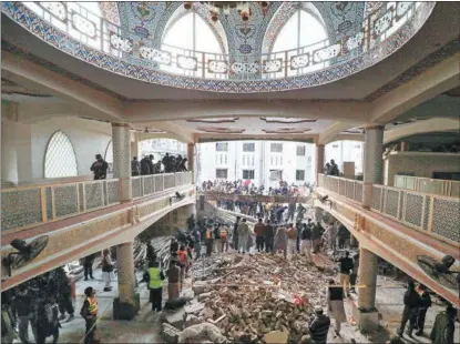  ?? FAYAZ AZIZ / REUTERS ?? Rescue workers and members of the public gather to look for survivors under a collapsed roof after a suicide bombing at a mosque in Peshawar, Pakistan, on Jan 30. The attack killed at least 100 people, mostly police officers.