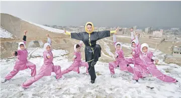  ??  ?? Afghan members of a wushu martial arts group led by trainer Sima Azimi (centre), 20, pose for a photograph at the Shahrak Haji Nabi hilltop overlookin­g Kabul. — AFP photos