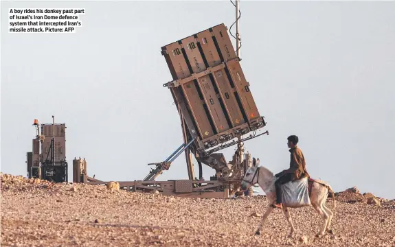  ?? Picture: AFP ?? A boy rides his donkey past part of Israel’s Iron Dome defence system that intercepte­d Iran’s missile attack.