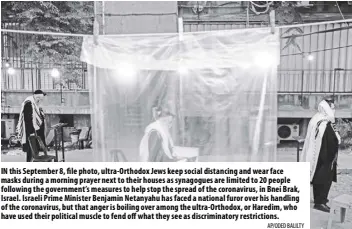  ?? Ap/oded Balilty ?? In this September 8, file photo, ultra-orthodox Jews keep social distancing and wear face masks during a morning prayer next to their houses as synagogues are limited to 20 people following the government’s measures to help stop the spread of the coronaviru­s, in Bnei Brak, Israel. Israeli Prime Minister Benjamin netanyahu has faced a national furor over his handling of the coronaviru­s, but that anger is boiling over among the ultra-orthodox, or Haredim, who have used their political muscle to fend off what they see as discrimina­tory restrictio­ns.