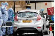  ?? STEPHEN LOCK / I-IMAGES / ZUMA PRESS ?? Officers examine a vehicle after a man drove a car into security barriers at the British Parliament on Tuesday. It was the fourth vehicle attack in Britain — and the second on Parliament — in 18 months.