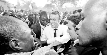  ??  ?? Macron greets people as he arrives to visit a school in Ouagadougo­u. — Reuters photo