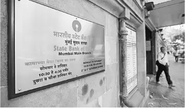  ??  ?? A man walks out of the SBI main branch in Mumbai, India. SBI, the country’s biggest lender by assets, said it had cut its lending rates by 90 bps for maturities ranging from overnight to three-year tenures, after experienci­ng a surge in deposits. —...