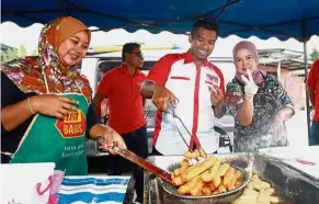  ??  ?? Popular snack: Muhammad Aiman choosing some yu tiao during the walkabout at the Beranang morning market.