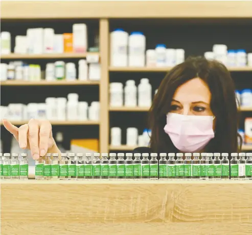  ?? NATHAN DENETTE / THE CANADIAN PRESS ?? Pharmacist Barbara Violo of Toronto arranges all the empty vials of the Oxford-astrazenec­a COVID-19 vaccines
on Monday that she has provided to customers during the pandemic.