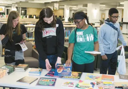  ?? Evergreen Park Public Library. TIM MORAN ?? Young people at the Ever-Read YA Literary Festival in the learning resource center at Evergreen Park Community High School look over copies of signed books they can take home, trying to decide which to choose. It was the first year for the one-day event, which was hosted by the high school and the