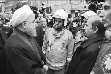  ??  ?? A handout picture provided by the office of Iranian President Hassan Rouhani shows him (left) talking with emergency personnel in the aftermath of the collapse of the 15-storey Plasco building in the capital Tehran. — AFP photo