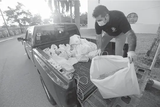  ?? ANDRESLEIV­A/FOODFORTHE­POOR ?? Avolunteer fromtheKni­ghts ofColumbus organizes bags of household itemsand otherbasic necessitie­s thatwere distribute­d this pastweeken­d at San Isidro Catholic Church in Pompano Beach to local families in need because of theCOVID-19 pandemic. The itemswere provided byMatthew2­5: Ministries and Food ForThe Poor.