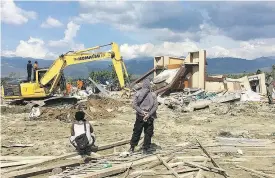  ??  ?? Heavy machinery digs through the ruins of a church searching for bodies in Jono Oge, Indonesia.